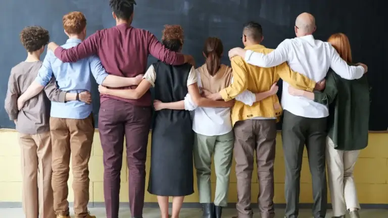 image of 8 people facing away from the camera with their arms over one another