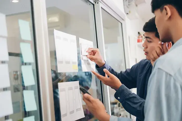 image of two people looking at notes that have been posted on a glass wall