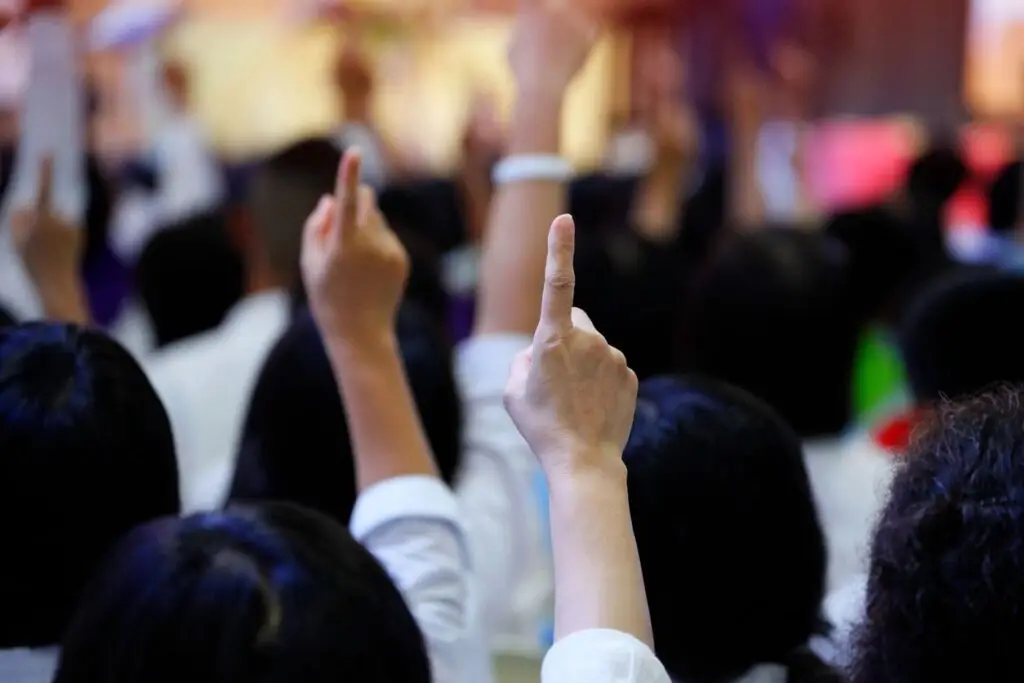 blurred image of people raising their pointer finger in the air from behind