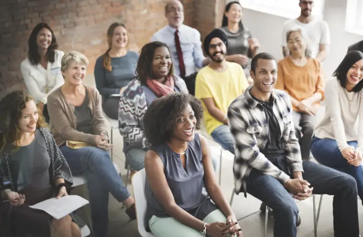 A group of people all sitting in chairs smiling at what is in front of them