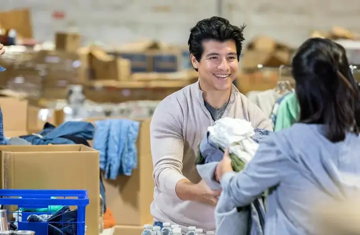 Image of a woman donating clothes and handing them to a man