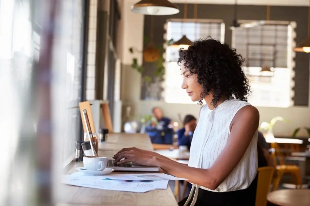 Image of a woman in a coffee shop working on her laptop