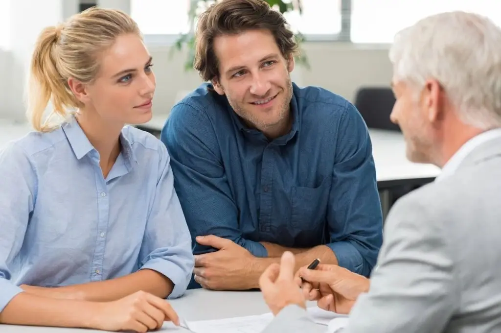 older man speaking with a younger man and woman over a table