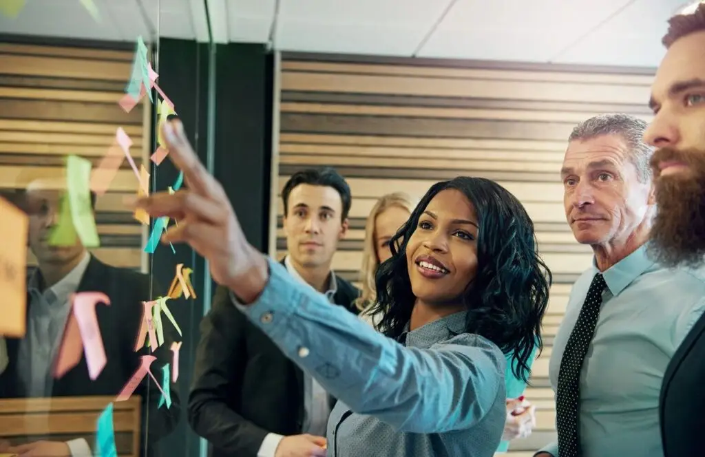 image of five people looking at this wall that is covered with post it notes