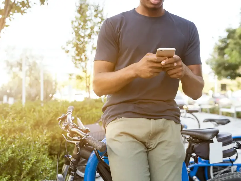 a man leaning against a bike while scrolling on his cell phone