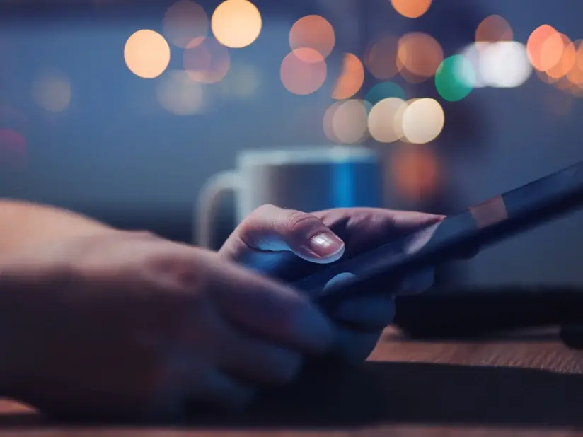 image of somebody on their phone in a dark lit room