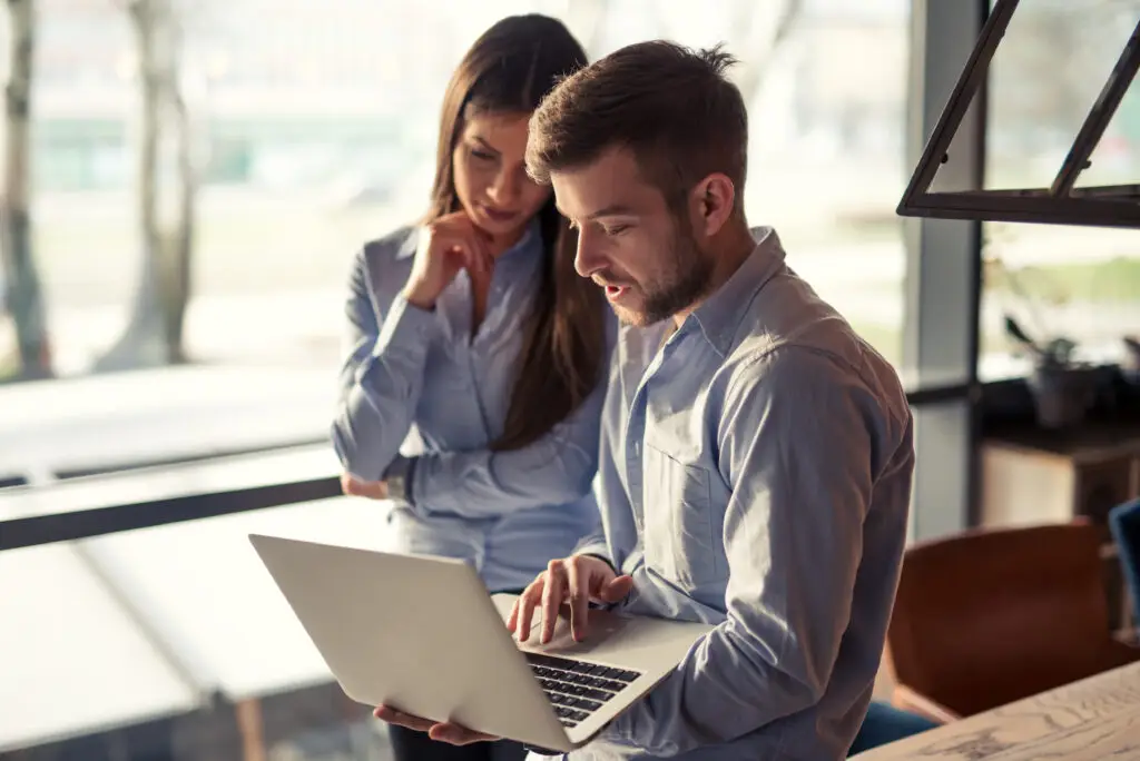 Two colleagues looking at a computer and discussing business.