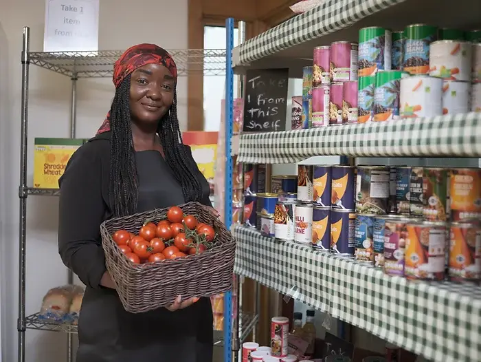 Image of a woman in a grocery pantry holding a basket full of tomatoes