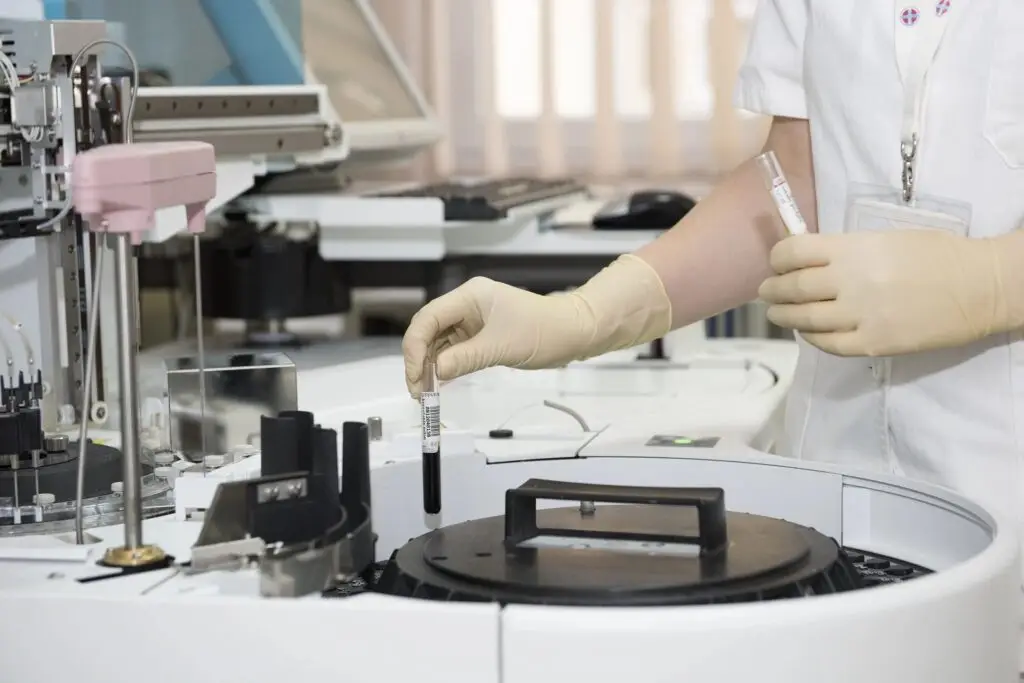 Image of a lab tech putting a test tube into a machine