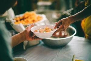 People holding a plate of food at soup kitchen