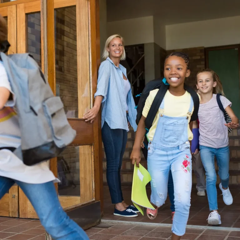 Group of elementary school children running outside at the end of the lessons. Happy school boys and girls running outside from school building. Finish school and summer vacation concept.